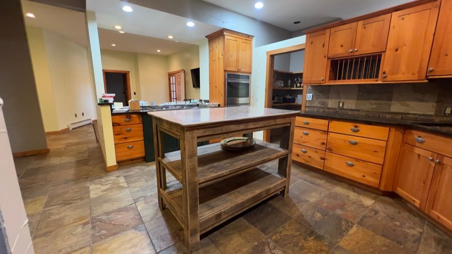 Kitchen with a wood island and stone tile floors